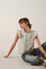 Camisa blanca de algodón con bordado calado y volados en los hombros.