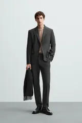 Pantalón de vestir gris oscuro, corte slim fit, con bolsillos laterales y traseros de ojal. Cierre frontal con cremallera y botón.