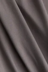 Vestido largo gris de punto elástico con leve brillo, corte entallado, escote drapeado, espalda escotada y pliegues laterales para crear un efecto drapeado. Sin mangas.