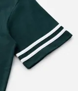 Remera de algodón color verde oscuro, corte relaxed, cuello redondo y manga corta. Presenta un pequeño estampado en el pecho con el texto "N.Y.U.S" en blanco y dos franjas blancas horizontales en cada manga.