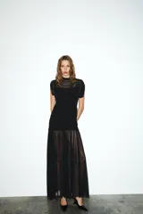 Vestido midi negro de cuello alto y sin mangas, con detalle drapeado en la parte superior y falda plisada. Incluye forro interior con tirantes finos ajustables y cierre lateral con cremallera oculta.