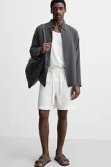 Bermuda regular fit negra confeccionada en tejido de lino. Cintura elástica ajustable con cordón y pliegues frontales. Bolsillos frontales y detalle de bolsillos traseros de plastrón.