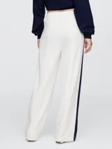 Pantalón deportivo azul marino de corte recto, con cintura elástica, bolsillos laterales y logo de Gap bordado en blanco. Presenta una franja blanca vertical en los laterales.
