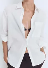 Camisa blanca de lino con cierre de botones, bolsillo de parche en el pecho, manga larga con puños abotonados, diseño recto y cuello camisero.