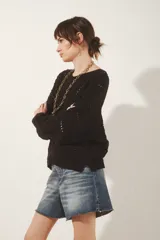 Sweater tejido de algodón color negro, con diseño de ochos y puntos calados, escote redondo y manga larga.