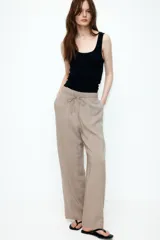 Pantalón de viscosa color beige, de corte amplio, tiro alto, cintura elastizada con cordón de ajuste, bolsillos laterales y piernas rectas.