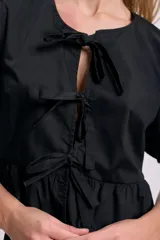Blusa negra con escote redondo y mangas cortas abullonadas. Presenta lazos frontales para ajustar el escote y un corte con frunce en la cintura.