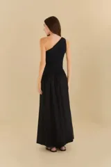 Vestido largo negro con un solo hombro, corte ajustado en el torso y falda acampanada.