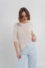 Buzo de punto abierto color beige, de corte oversize, con mangas 3/4 y terminaciones acanaladas.