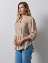 Blusa color beige de gasa, marca Figueroa & Flower. Cuello a la base, escote en V y abertura central con botones. Hombros y espalda en crochet. Manga 3/4 amplia con puño y botón.