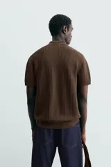 Polo gris de punto con textura, corte regular fit, cuello solapa y cierre frontal con botones.