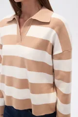 Sweater de tejido de punto, holgado, con rayas horizontales anchas en blanco y negro. Presenta cuello polo con escote en V y mangas largas.
