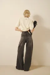 Jean oxford tiro alto de denim negro con lavado stone y bigotes. Pierna ancha desde la cadera.