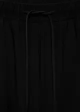 Pantalón negro de tejido fluido con cintura elástica ajustable con cordón. Diseño recto de tiro alto con bolsillos laterales.