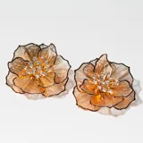 Aros colgantes dorados con forma de flor y apliques de strass.