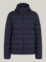 Campera Tommy Hilfiger acolchada color azul marino, con capucha fija ajustable con cordón, cierre de cremallera frontal, dos bolsillos laterales y parche engomado con el logo de la marca en la manga.