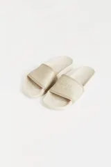 Ojotas de goma color beige con tira ancha sobre el empeine y logo de la marca en relieve.