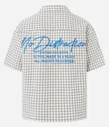 Camisa de hombre de manga corta, cuello inglés y corte boxy, confeccionada en algodón tricolina texturizada a cuadros. Presenta abotonado frontal y bordado en la espalda.