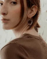 Aros colgantes con forma circular, hechos de resina color lila y borde de strass plateado. El aro es de acero quirúrgico plateado.