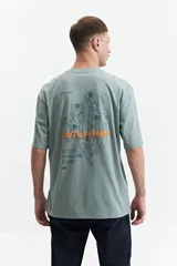 Remera de manga corta color verde con estampado de flores y texto en la espalda.