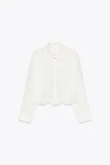 Camisa blanca corta de cuello solapa y manga larga. Bajo con bordados perforados combinados a tono. Cierre frontal con botones.