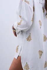 Camisa blanca de manga larga con bordado de hojas doradas.