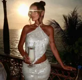 Top blanco con lentejuelas, escote halter y espalda descubierta.
