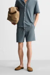Bermuda azul de tejido con mezcla de algodón, corte relaxed fit, cintura elástica ajustable con cordón, bolsillos delanteros y detalle de bolsillo trasero de vivo.