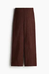 Pantalón marrón de punto con textura arrugada, corte holgado, tiro alto, cintura elástica y piernas rectas.