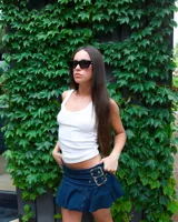 Minifalda plisada de mezclilla oscura con costuras blancas contrastantes. Presenta un cinturón incorporado con dos hebillas metálicas grandes y ajustables.