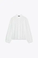 Camisa blanca de manga larga con cuello con volantes y bordados perforados. Cierre frontal con botones a tono.