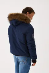 Campera Wrangler de hombre, modelo Teddy, color azul marino con capucha desmontable con borde de piel sintética, cierre frontal con cremallera y botones a presión, bolsillos laterales con solapa y puños y cintura acanalados en negro.