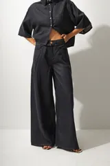 Pantalón de jean de tiro alto color negro, con corte wide leg y detalle de cinturón con hebilla metálica.