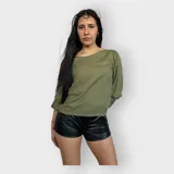 Camisa color verde oliva de tela suave y fresca, con escote redondo y mangas tres cuartos abullonadas con puño elástico. Lazo en la parte posterior.