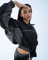 Campera deportiva bomber negra con recortes y vivos blancos.