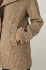 Chaquetón marrón de lana con cuello, abrochadura simple con botón en el cuello, bolsillos ojal y detalle de martingala en mangas.