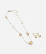 Conjunto de accesorios que incluye un collar largo y un par de caravanas. El collar presenta una cadena fina dorada con esferas de diferentes tamaños en tonos blanco perlado y dorado mate. Las caravanas son de diseño colgante con tres esferas alineadas verticalmente en los mismos tonos. Confeccionado en metal reciclado con baño de oro mixto.