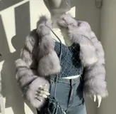 Chaqueta corta de piel sintética color gris con cuello alto y cierre metálico.