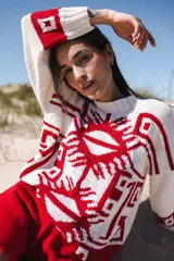 Sweater de algodón color crudo con jacquard geométrico en rojo en la parte delantera, trasera y mangas. Tiene cuello redondo y corte oversize.