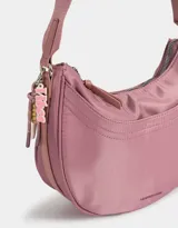 Bandolera hobo negra de tela deportiva con correa regulable, cierre superior, bolsillo frontal y charm lateral decorativo.