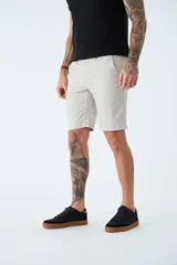 Bermuda color beige de corte chino, con bolsillos laterales, cierre con cremallera y botón, presillas para cinturón y logo bordado. Confeccionada en lino y algodón.