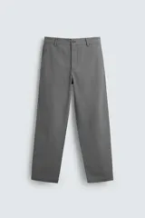 Pantalón chino color beige, de corte recto y tiro medio. Confeccionado en tejido de algodón con elasticidad, con bolsillos laterales y traseros de vivo. Cierre frontal con cremallera y botón.