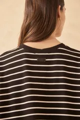 Vestido corto a rayas horizontales blancas y negras, con cuello redondo y mangas cortas. Presenta un estampado frontal con la palabra "L'AMOUR" en rojo y una flor roja. Tiene un tajo lateral en el ruedo.