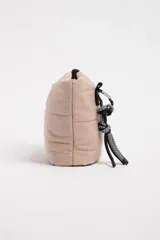 Necesser de poliéster color beige con diseño capitoneado y cierre superior con cremallera negra.