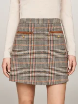 Minifalda de tweed de cuadros en tonos neutros, con botones dorados en los bolsillos y corte acampanado.