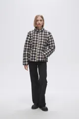 Campera puffer estampada a cuadros en blanco y negro con pequeños corazones rosados, cierre frontal con cremallera y bolsillos laterales.