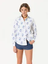 Camisa blanca de poplin con lycra y estampado de hongos en azul. Tiene ojales color bordó en la cartera y puños, y costura de refuerzo en forma de X en el puño.
