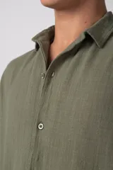 Camisa de lino color blanco, de manga corta, con cuello clásico y cierre frontal con botones.