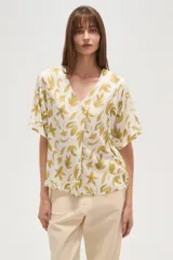 Blusa de viscosa estampada con motivos de hojas color dorado sobre fondo blanco, corte holgado y escote en V.