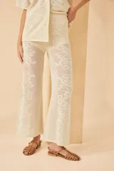 Pantalón tejido color crudo, con diseño calado de corazones y arabescos. Corte palazzo.